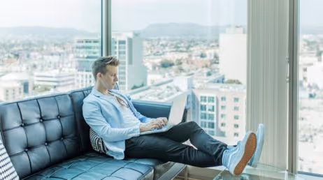 Man working on a laptop in a modern office with city view