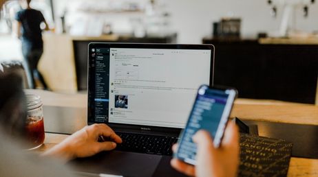 Person using laptop and smartphone for work communication