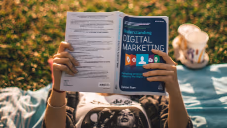 Person reading digital marketing book outdoors