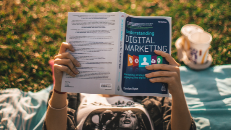 Person reading digital marketing book outdoors