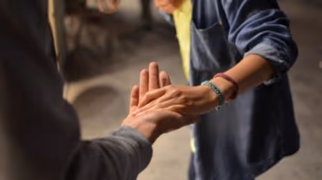 Two people reaching out and holding hands in a supportive gesture