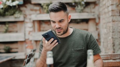 Man using voice command on smartphone outdoors