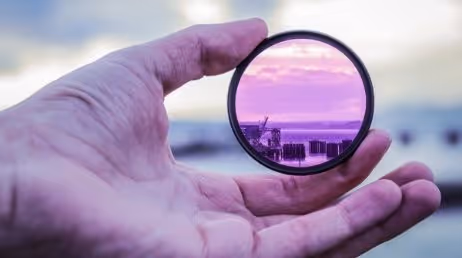 Hand holding purple lens filter with scenic view