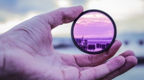 Hand holding purple lens filter with scenic view