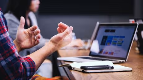Person gesturing during laptop discussion meeting