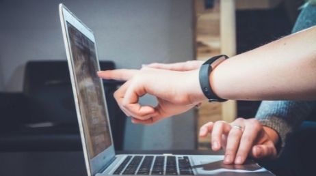 Person pointing at a laptop screen during discussion