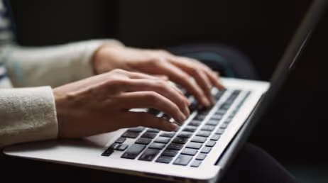 Person typing on a laptop keyboard close-up