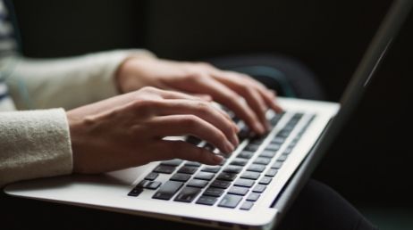 Person typing on a laptop keyboard close-up