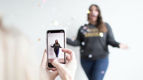 Person recording a video of woman with confetti"