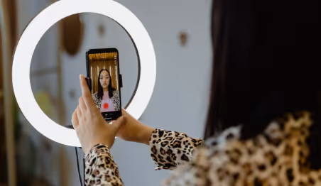Woman recording herself with phone and ring light