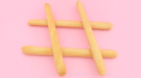 Hashtag symbol made from breadsticks on pink background