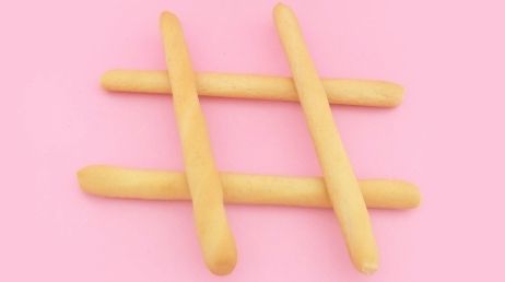Hashtag symbol made from breadsticks on pink background
