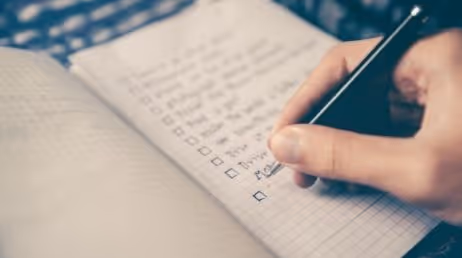 Person writing a checklist in a notebook