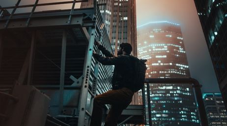 Person climbing building in city at night