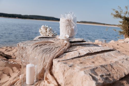 Eine sehr schön dekorierte Hochzeitstorte mit einem großen See als Hintergrund.