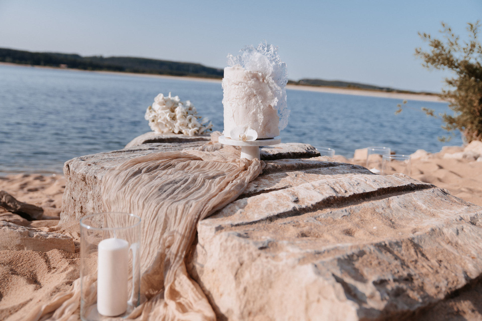 Eine sehr schön dekorierte Hochzeitstorte mit einem großen See als Hintergrund.