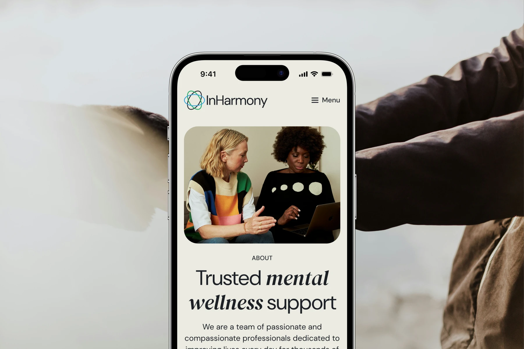 Smartphone screen showing InHarmony website with two women discussing something on a laptop and text about trusted mental wellness support.