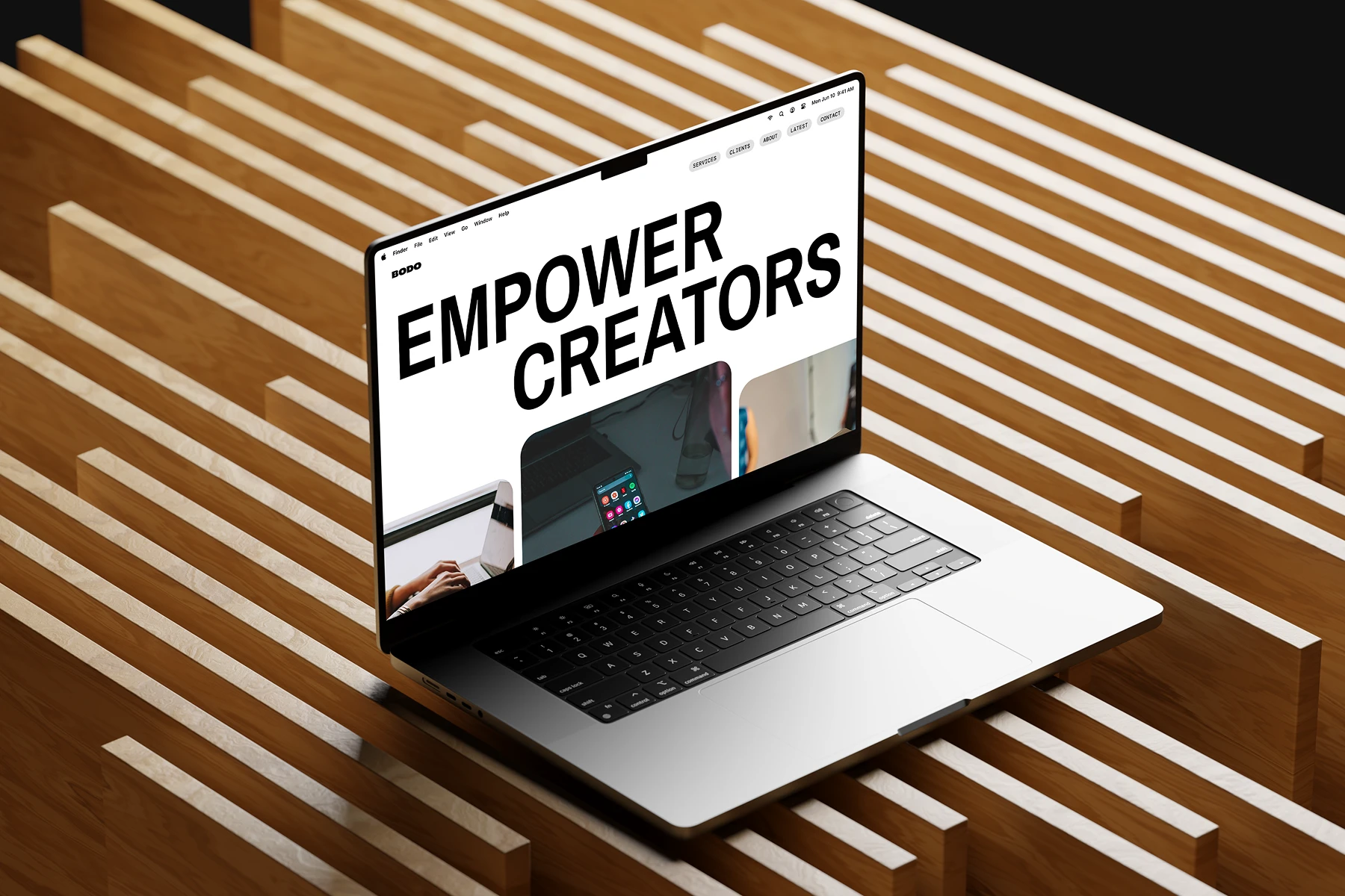Open laptop on wooden surface displaying a website with large text reading 'EMPOWER CREATORS'.