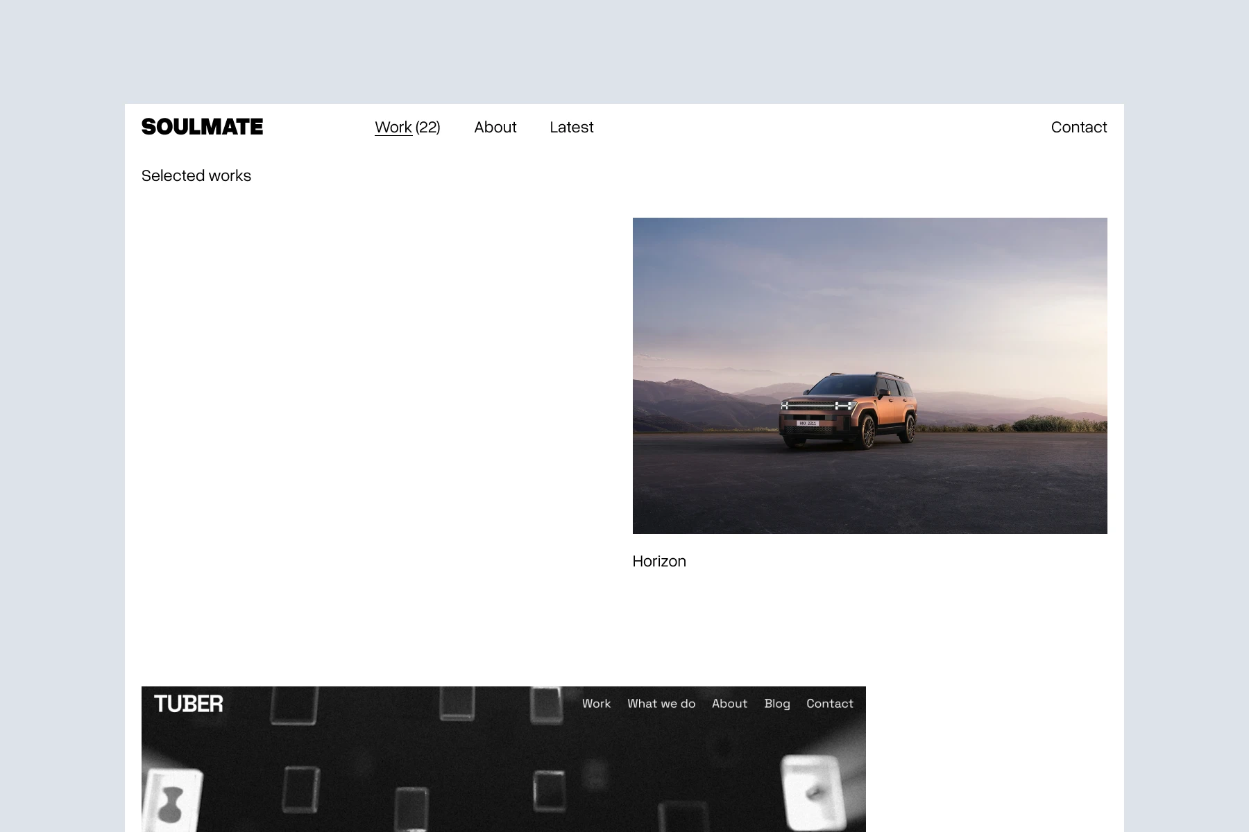 Orange SUV parked on a flat surface with mountains and a cloudy sky in the background at sunset.