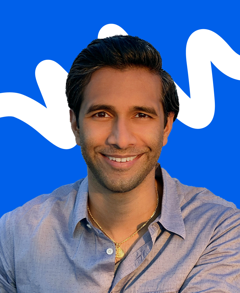 Smiling man with dark hair wearing a light blue shirt and gold necklace against a blue background with white abstract shapes.