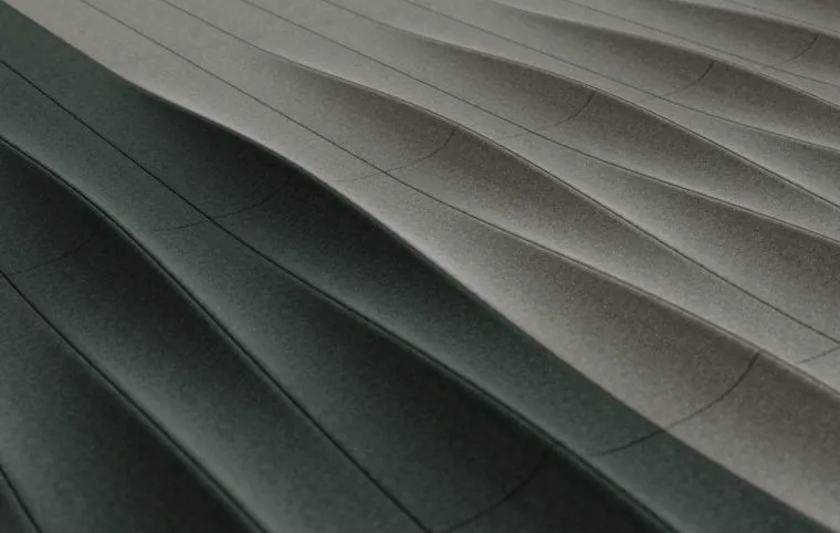 Close-up of curved, stitched fabric panels in dark green and light grey tones.