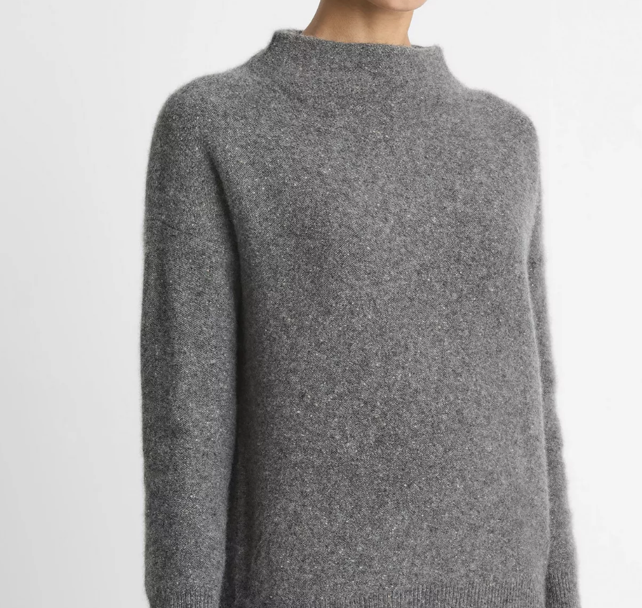 Close-up of a person wearing a fuzzy gray knit sweater with a mock neck and long sleeves.