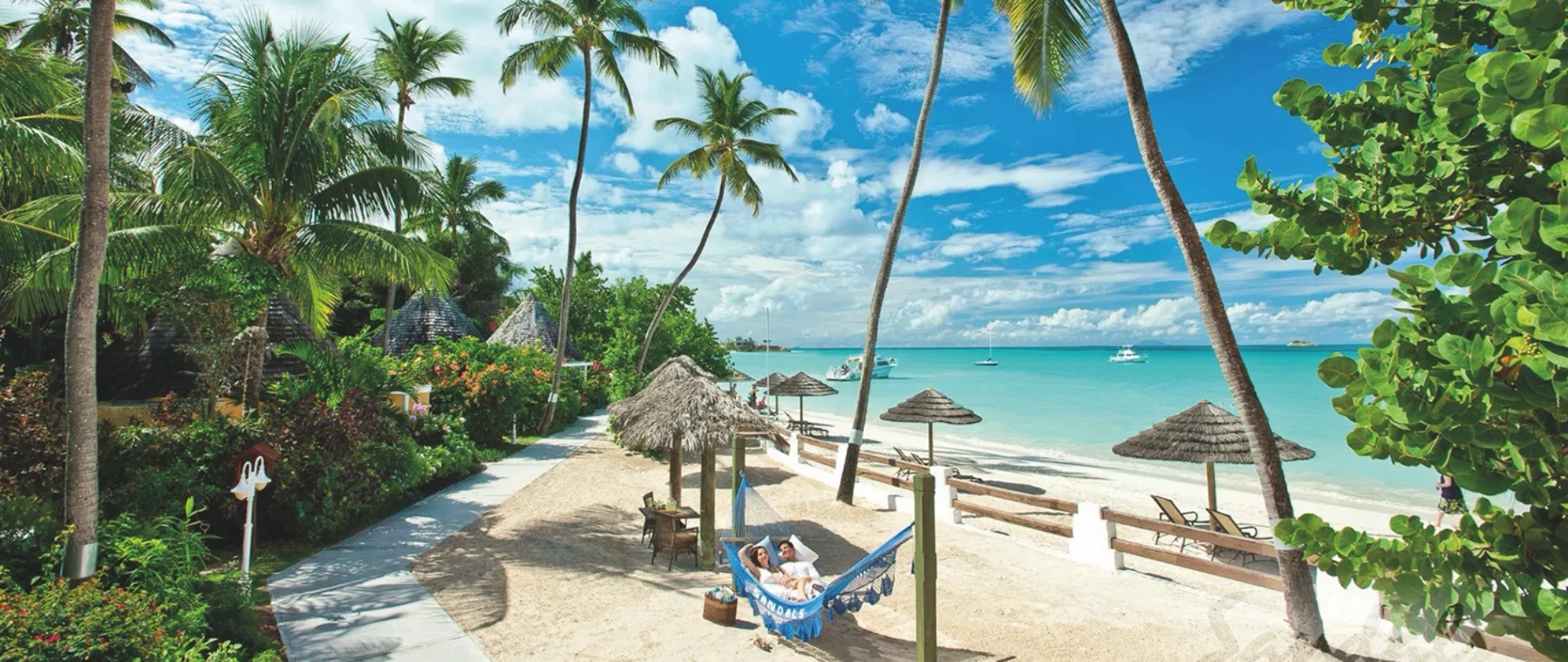 Tropical beach resort with palm trees, hammock, and turquoise waters