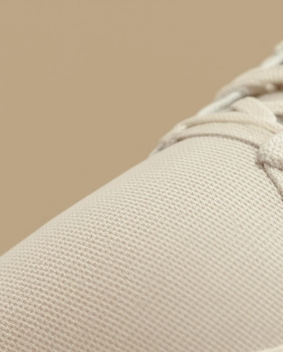 Close-up of beige textured fabric with woven pattern and cream-colored laces.