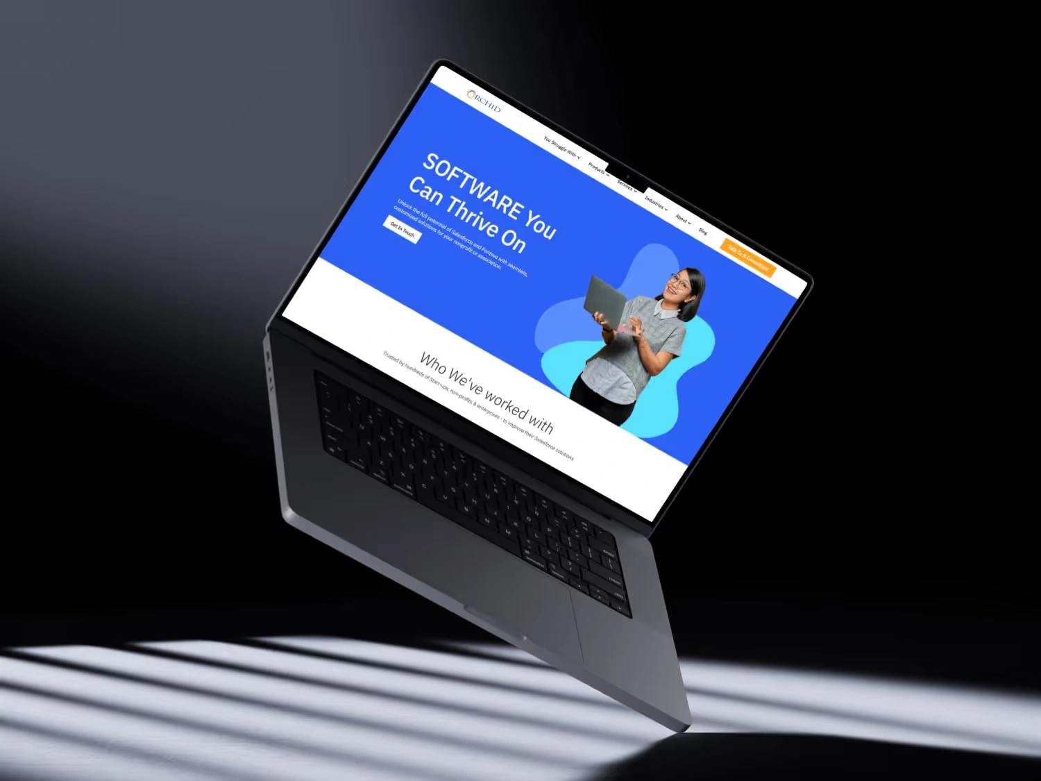Open laptop floating above ground displaying a blue webpage with a woman holding a tablet and text about thriving with software.