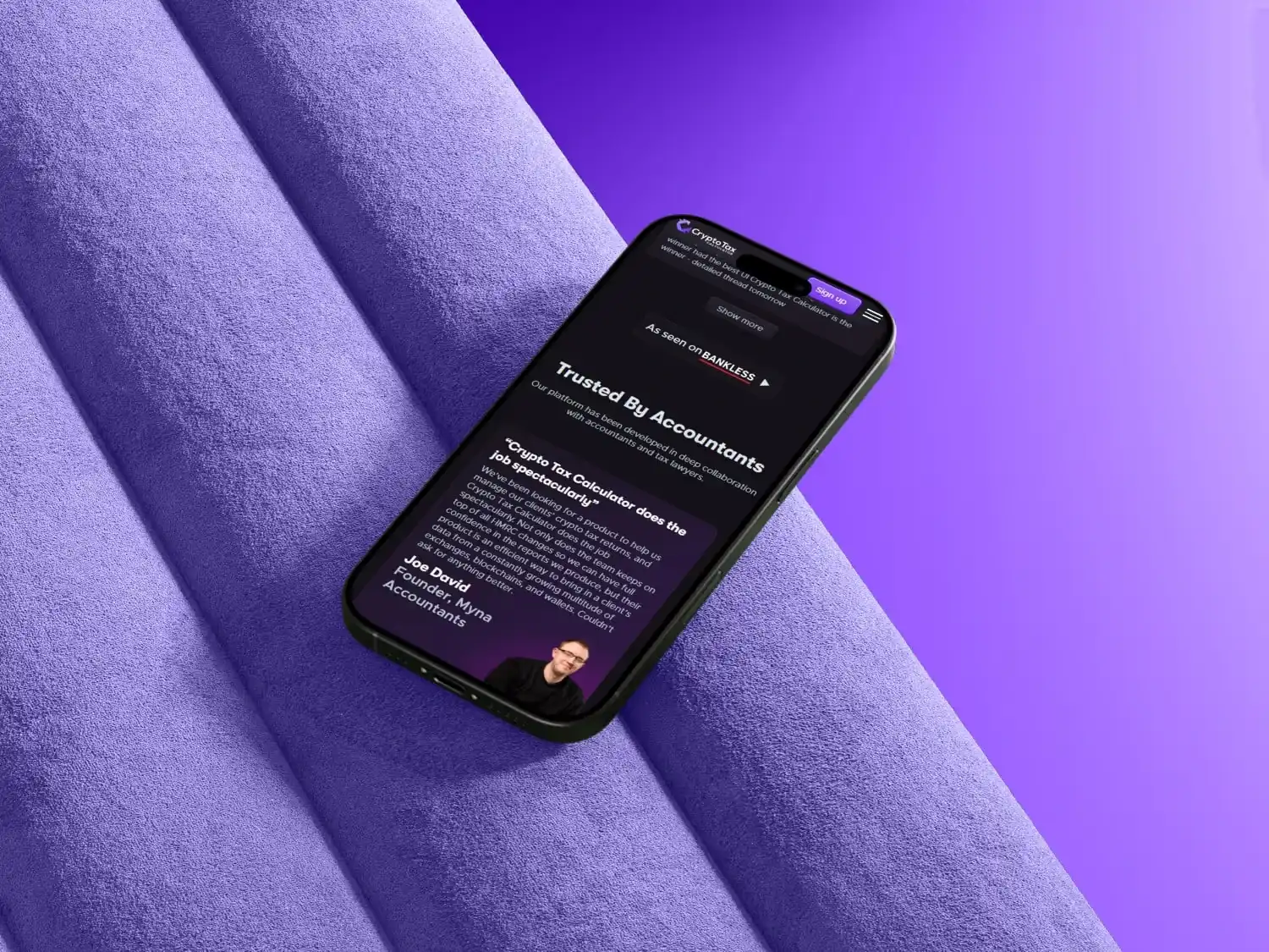 Smartphone displaying a crypto tax calculator website page with a testimonial from an accountant, placed on textured purple fabric rolls.