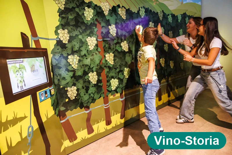 Bambino e visitatrici al muro interattivo delle vigne, gioco della vendemmia — Vino-Storia Colmar