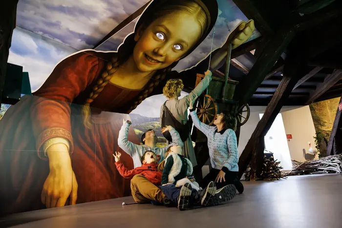 Familie im Saal der Elsässer Legenden vor einer riesigen Kulisse mit einer mittelalterlichen Figur — Wax of Legends Colmar