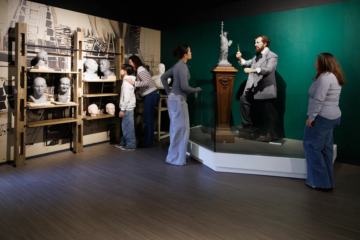Visitors in front of the model of the Statue of Liberty and the statue of Bartholdi, at Wax of Legends
