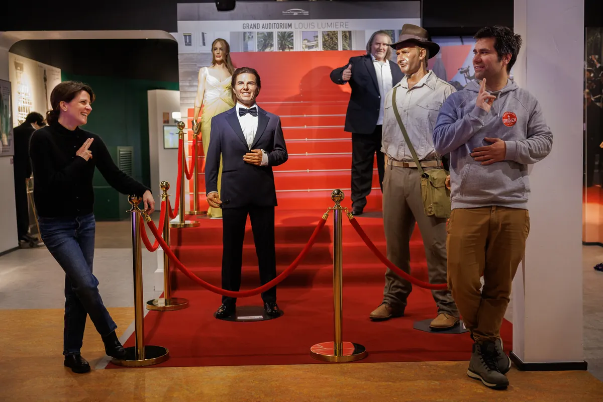 Visiteurs posant sur le tapis rouge, aux côtés des statues de cire de l'espace cinéma du Wax of Legends