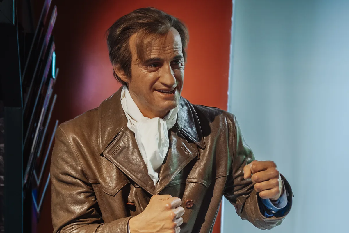 Wax figure of Jean-Paul Belmondo in a leather jacket, fists raised in a boxing stance, at Wax of Legends in Colmar
