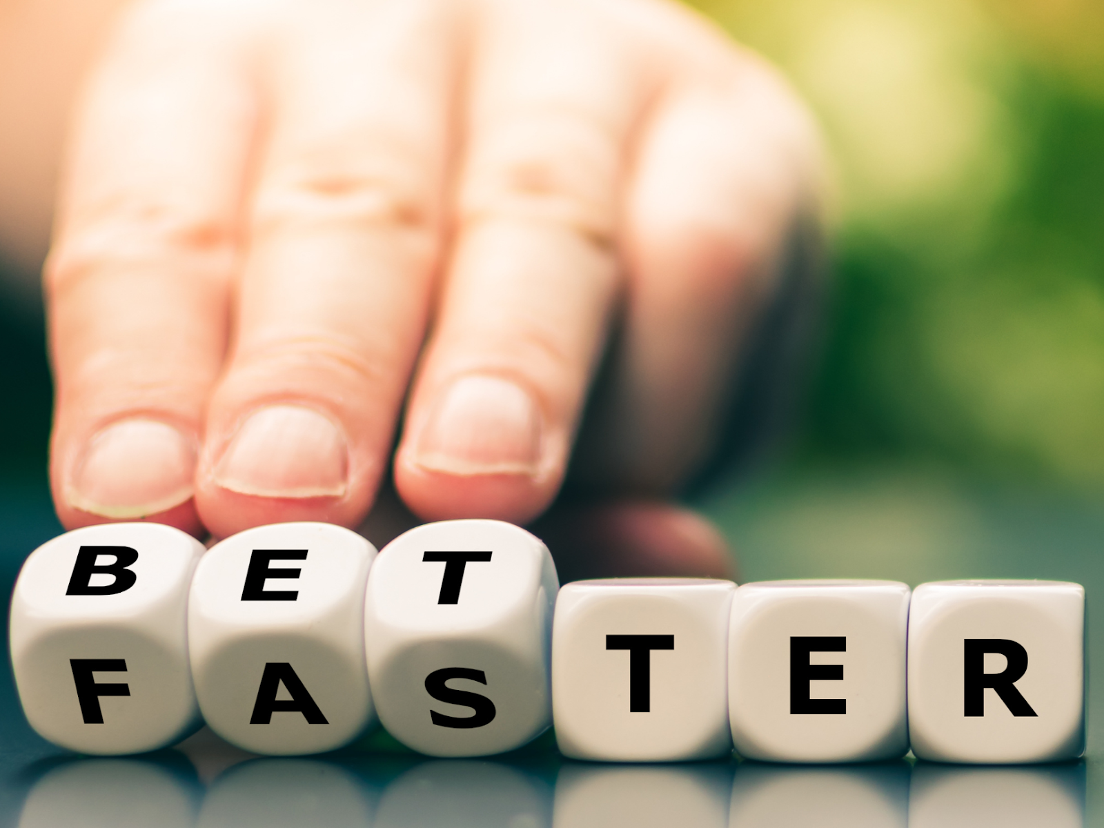 An image of lettered dice that spell out BETTER and FASTER simultaneously. 