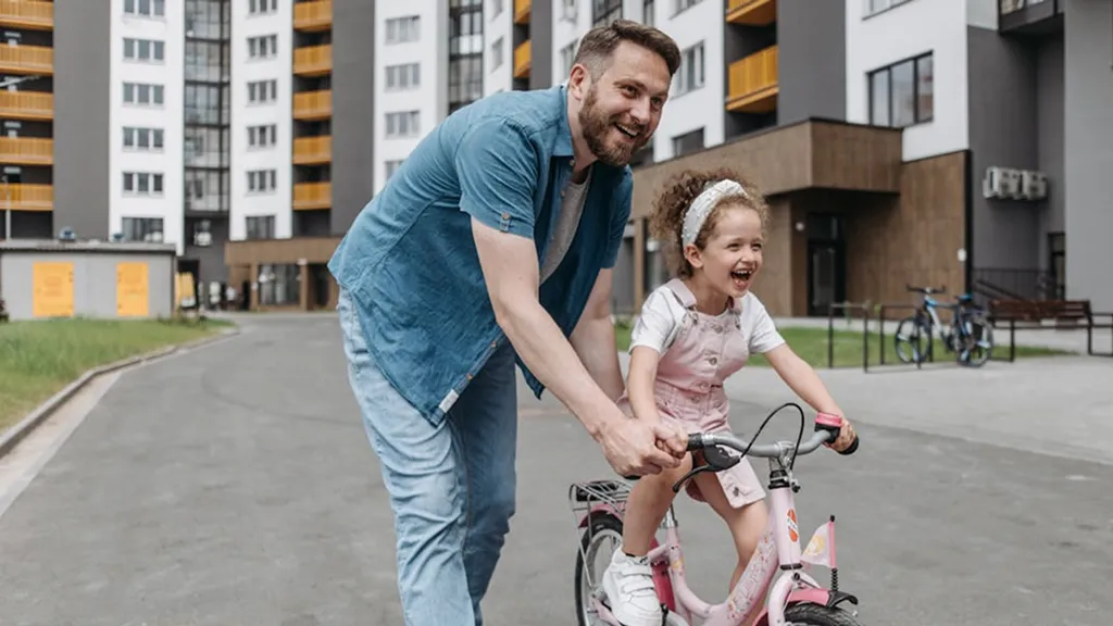 Long-term health habits illustrated by a parent helping a child learn to ride a bike, symbolizing guidance and consistency
