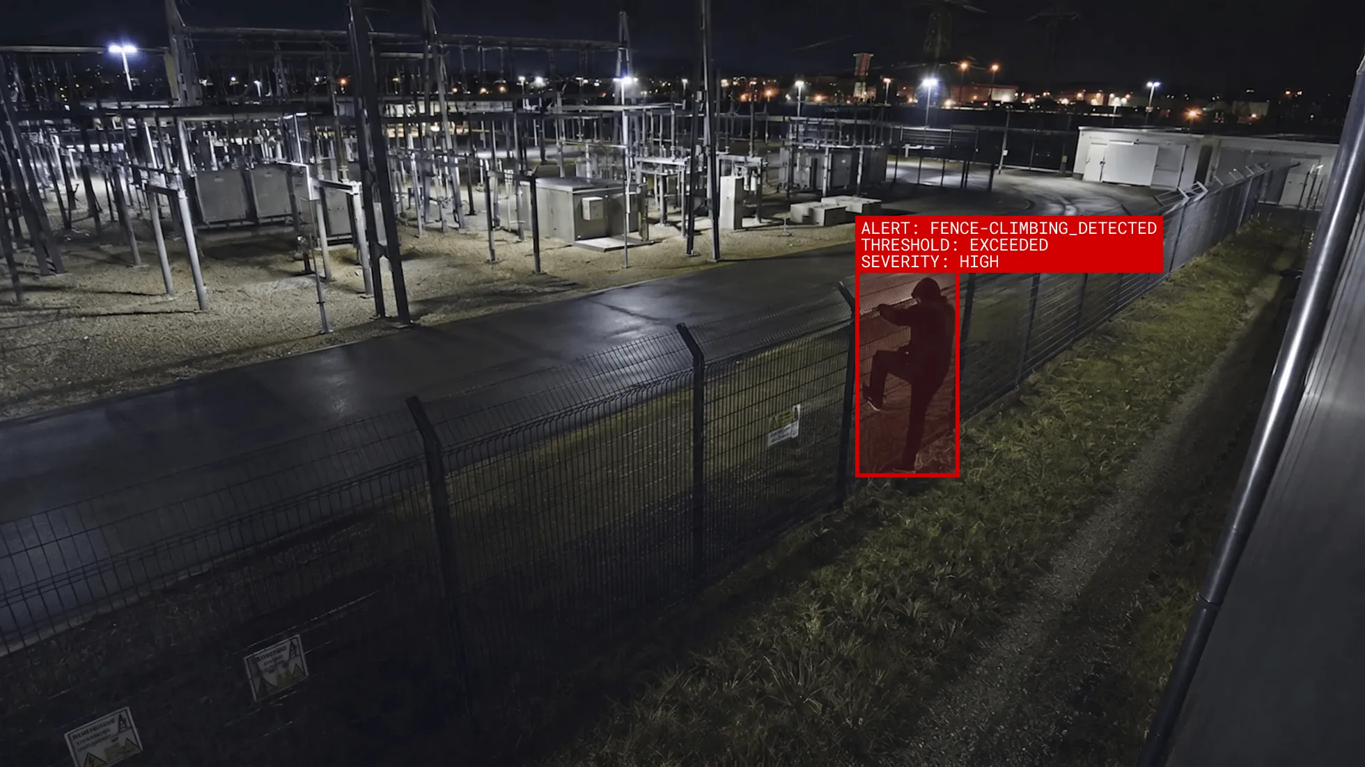 Staige KI erkennt live wie ein Eindringling klettert nachts über einen Sicherheitszaun in einer Umspannwerke, Alarmmeldung sichtbar.