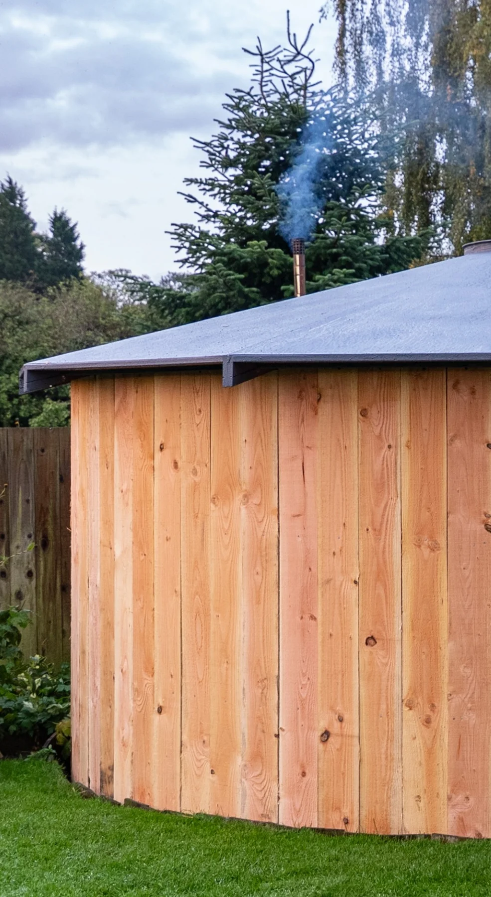 Wooden garden shed with an open half-door, stone steps leading up to it, and a sunset sky in the background.