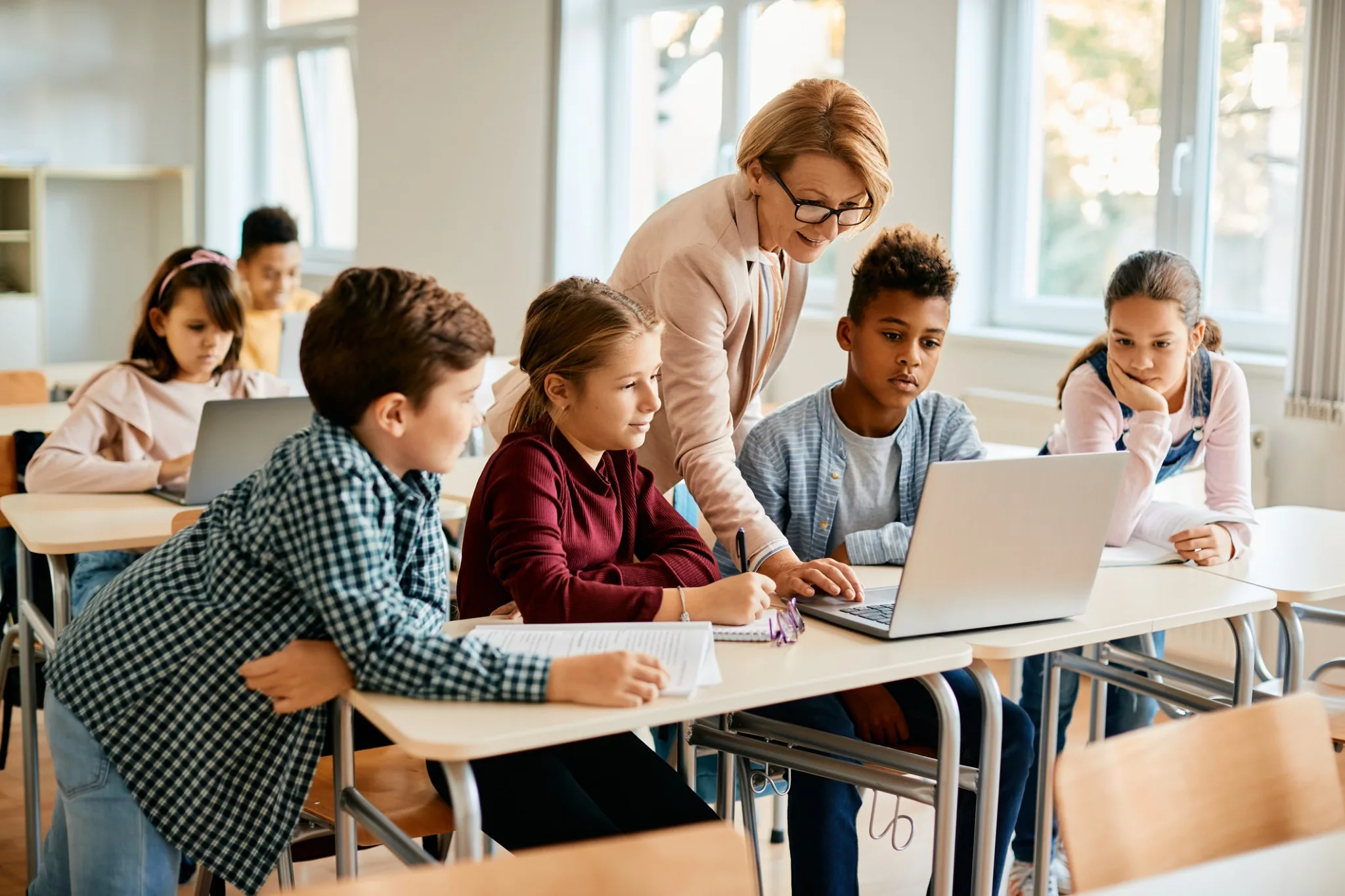 Teacher helping students at a desk.