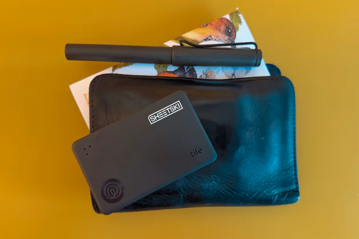 A wallet, pen, and bluetooth tracking card with a logo on it. 