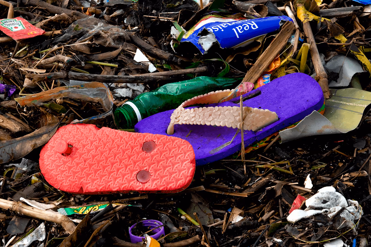 A pile of washed up garbage with plastic sandals front and center. 