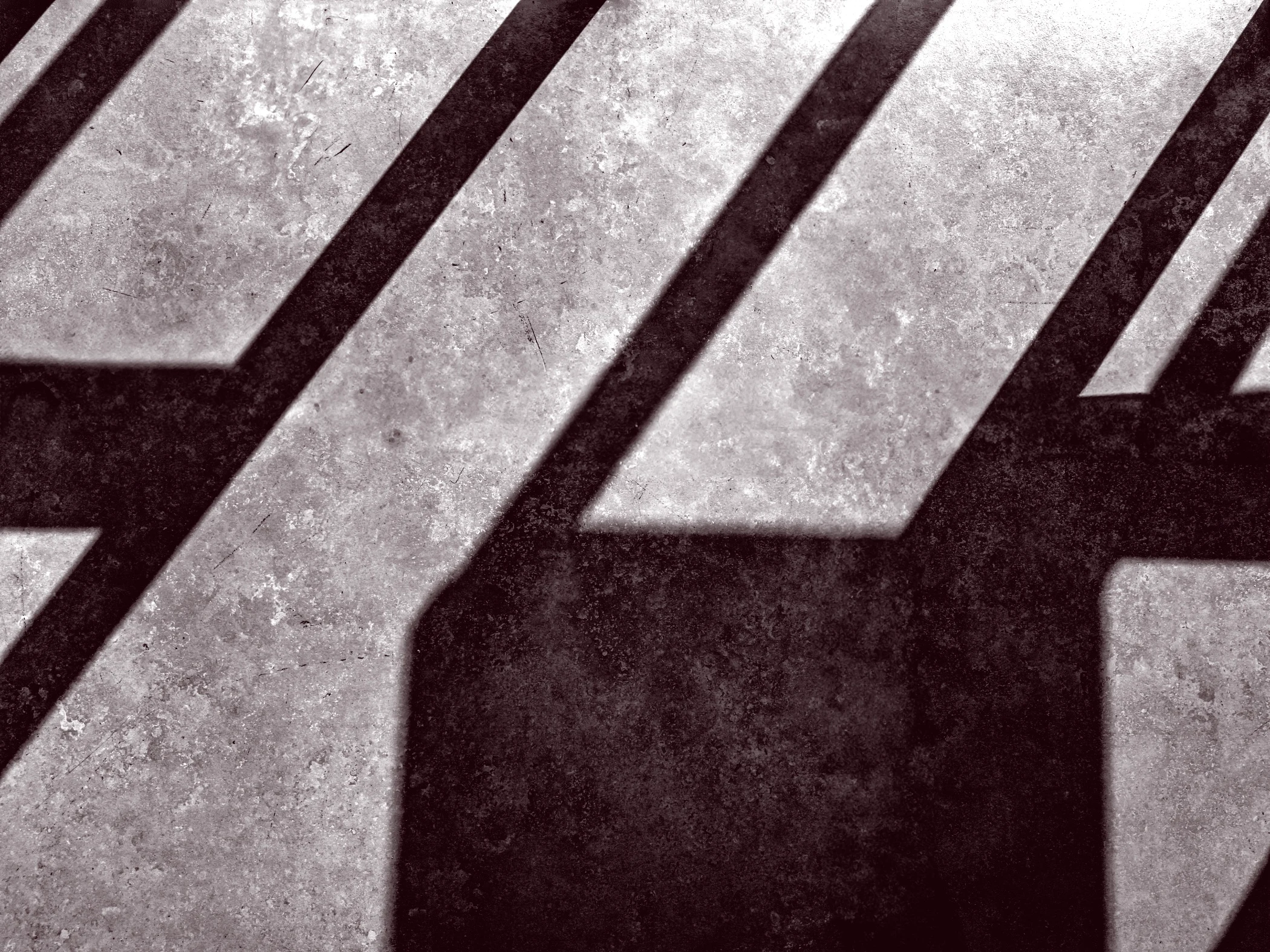 Dark geometric shadows cast on a textured concrete surface.