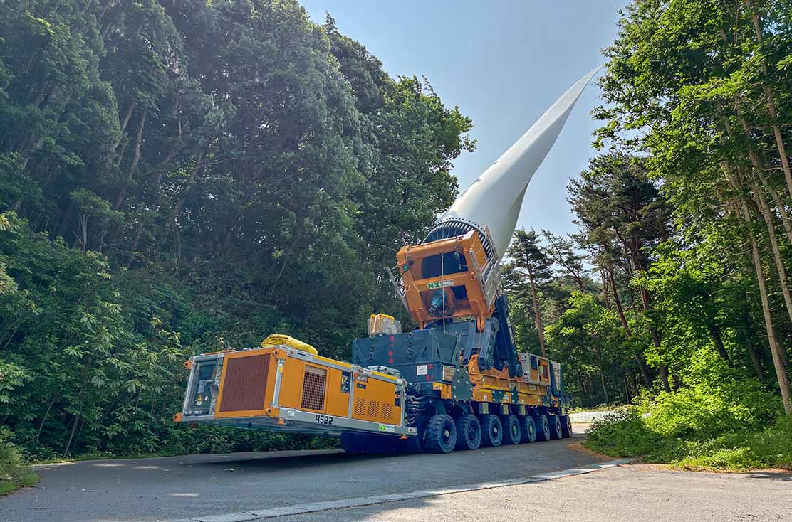 BladeMAX from the Company Cometto, used by the company Nippon Express with a rotor blade attached to it, driving through a forest by day.