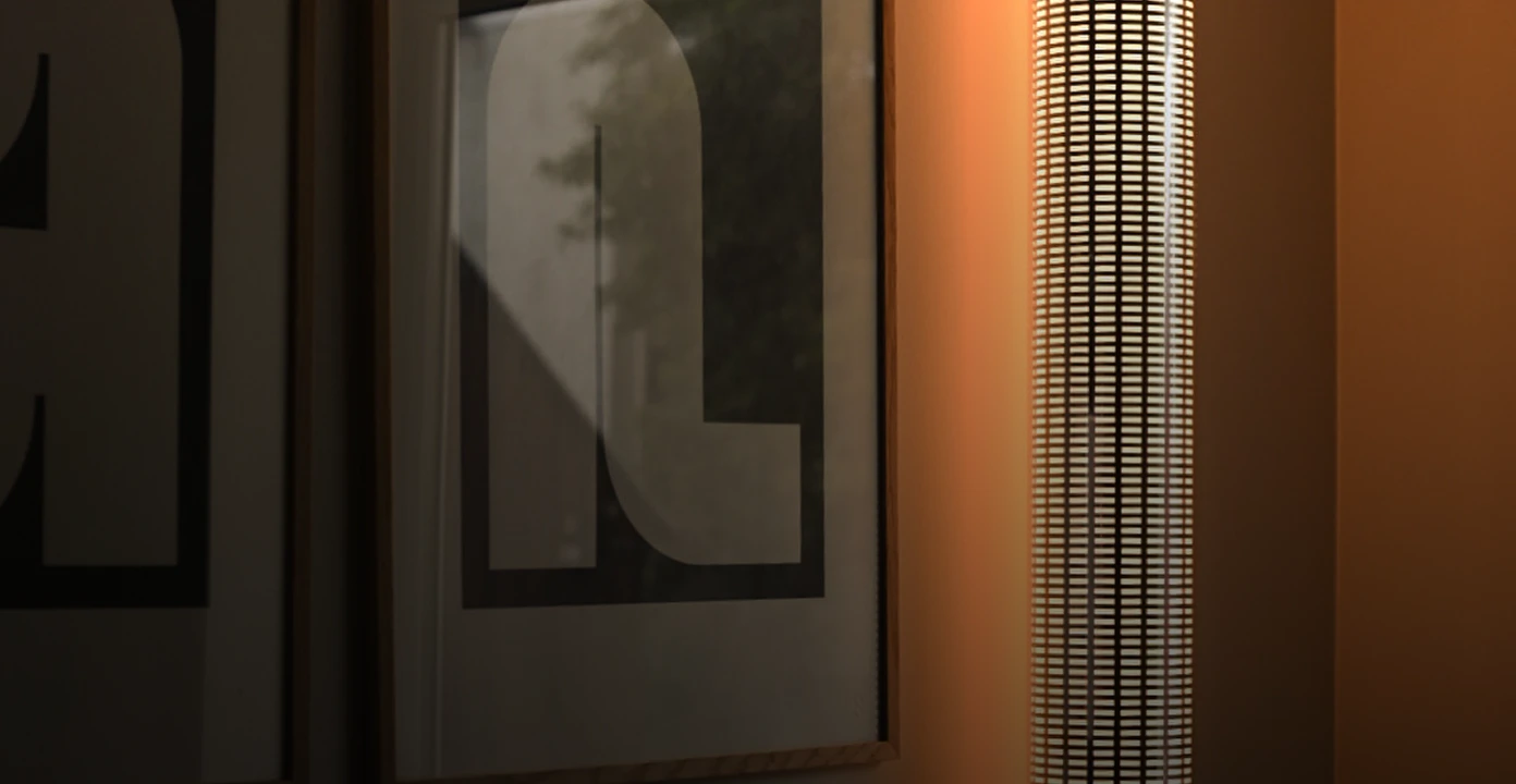 A modern vertical cylindrical lamp with a grid pattern casting warm light next to a framed abstract print on a muted wall.