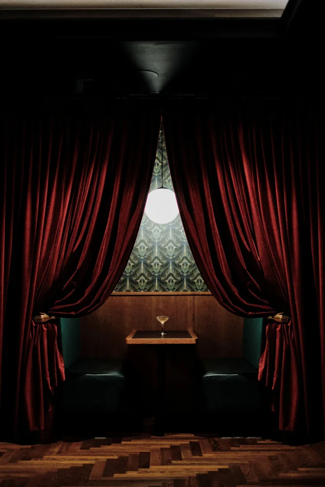 Booth framed by red velvet curtains at The Porter's Store cocktail bar, Jersey