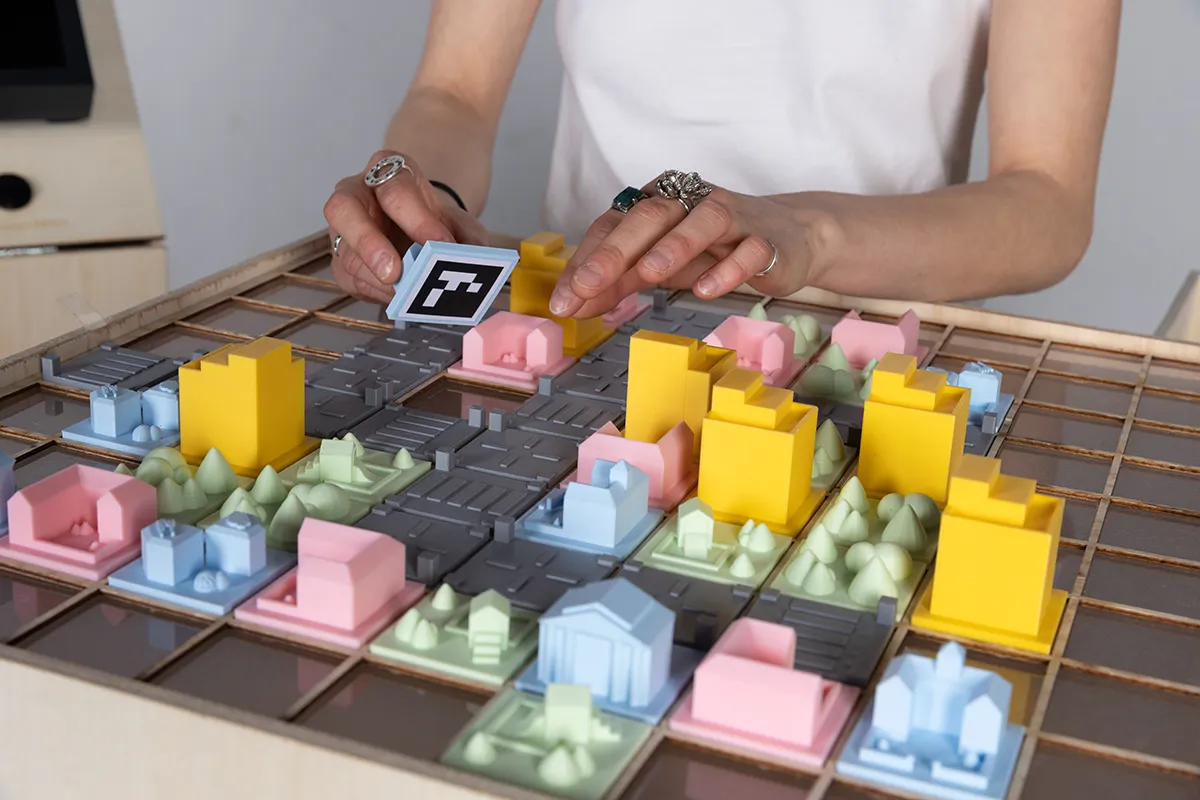 A person playing with Urbanova on the grid, revealing the ArUco Codes underneath.