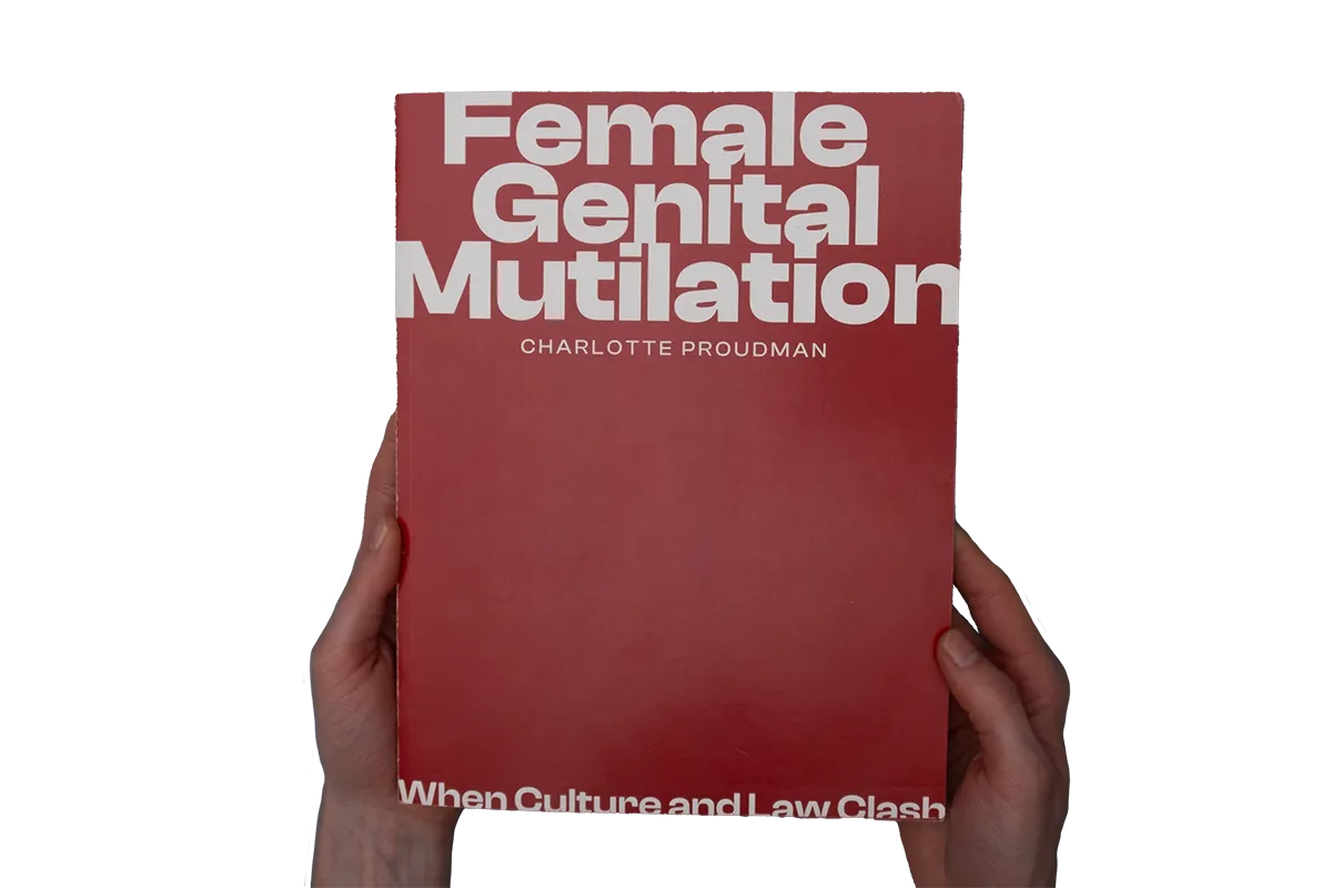 Hands holding a magazine with the title "Female Genital Mutilation".