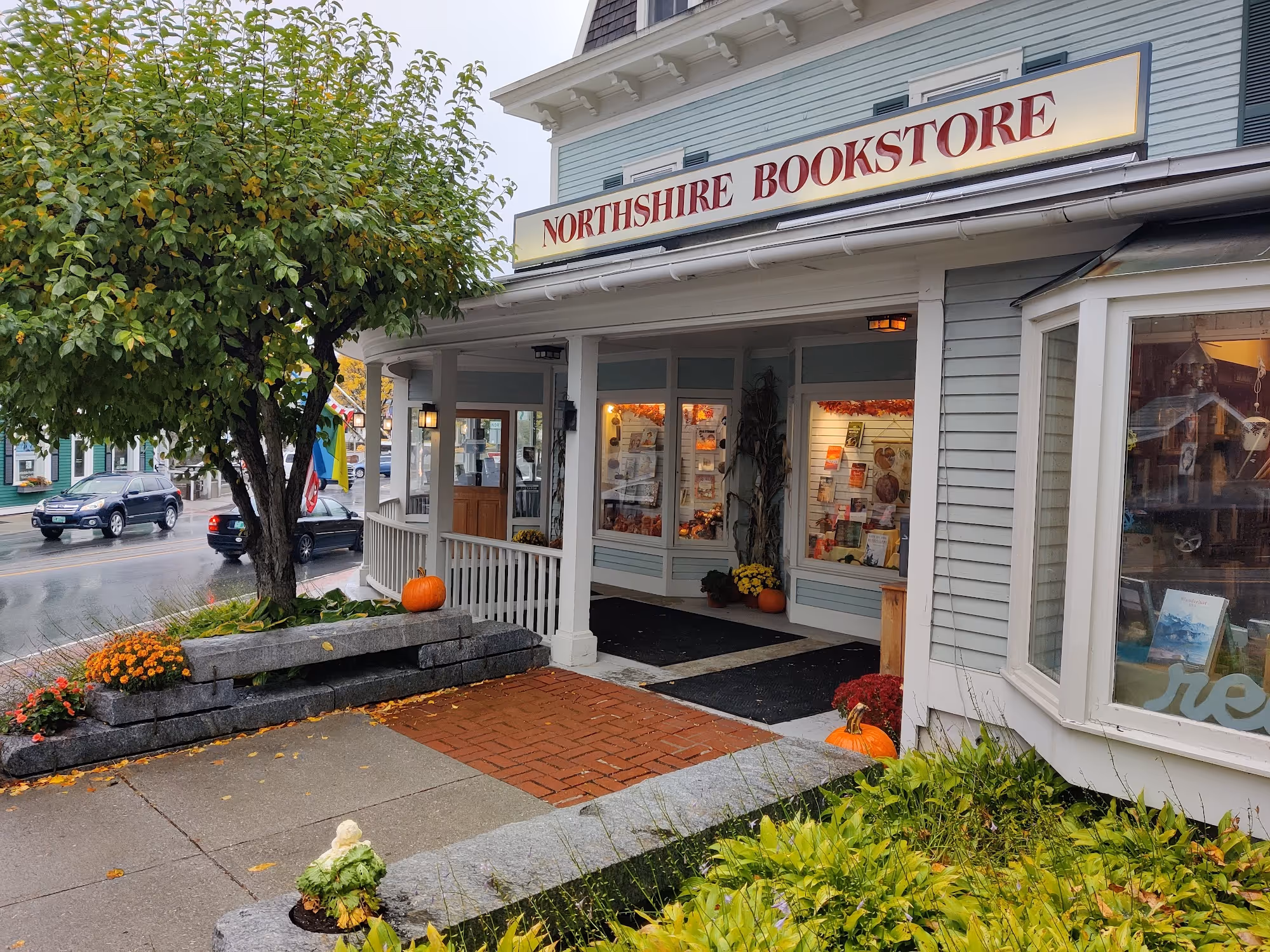 Cozy museum store interior with wooden shelves and tables displaying books, cards, and gifts, with a child reaching for items.