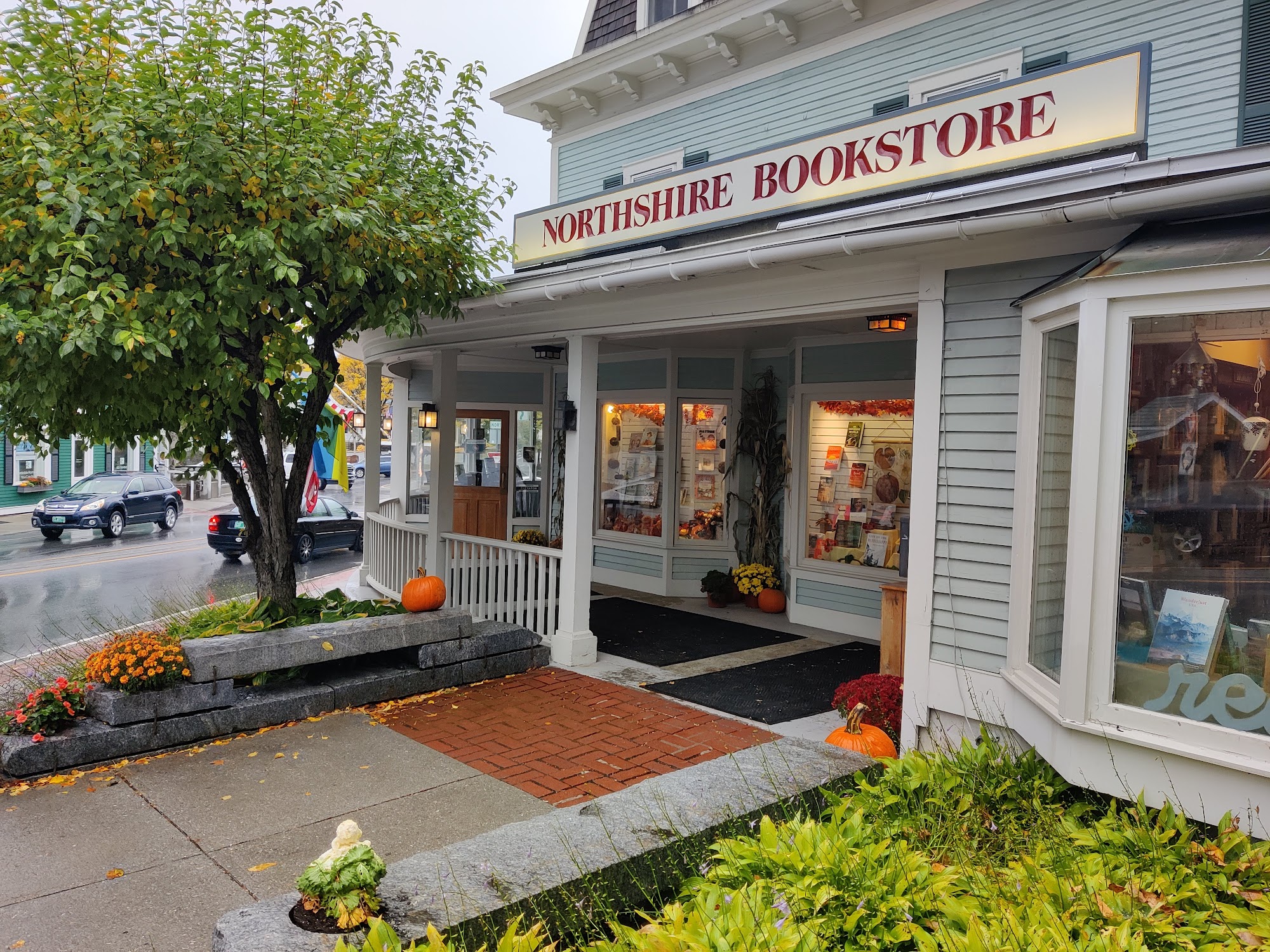 Cozy museum store interior with wooden shelves and tables displaying books, cards, and gifts, with a child reaching for items.
